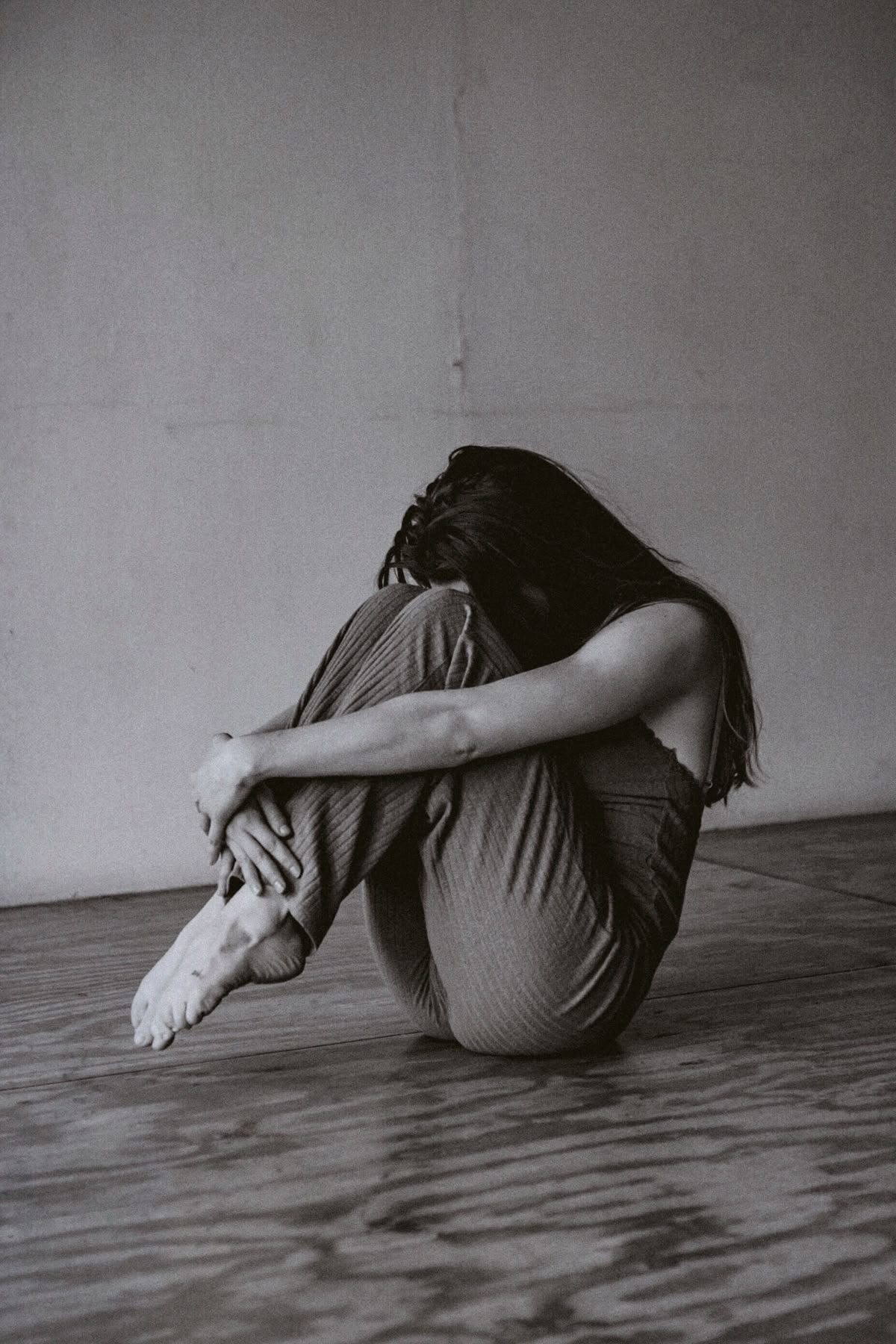A person sitting on the floor hugging their knees